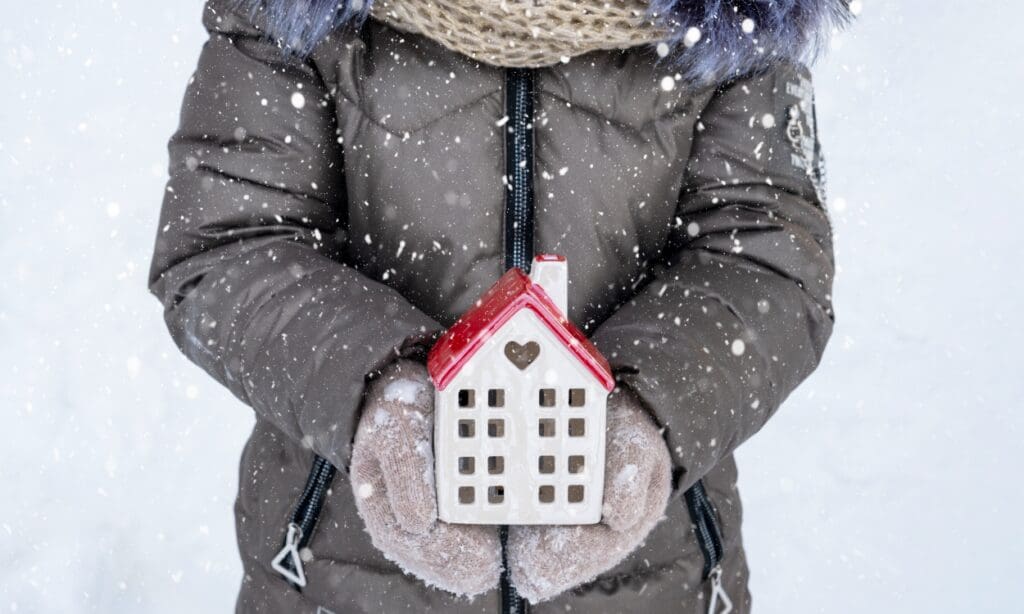 Child holding a toy house in the snow